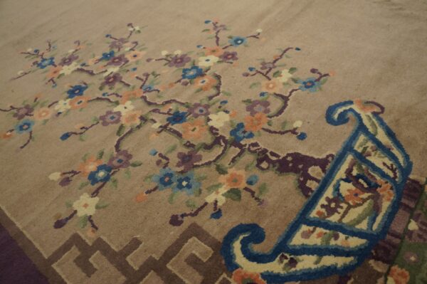 Muted tan rug with colorful blue, purple, and peach floral branches and a complex scrolled border.