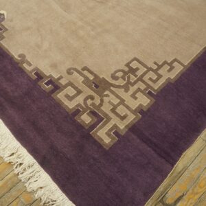 Low-pile rug in tan and purple featuring a detailed geometric border design on distressed light wood floors.