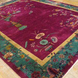 Magenta rug with scattered floral and avian motifs, framed by teal and gold borders, on wood planks.