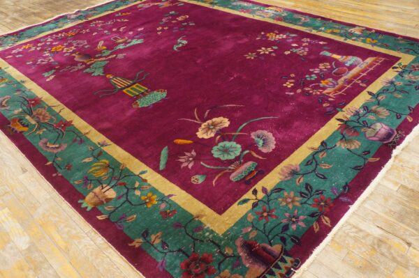 Magenta rug with scattered floral and avian motifs, framed by teal and gold borders, on wood planks.