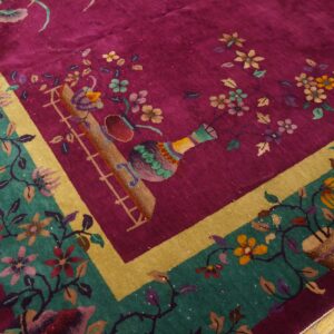 Vibrant magenta rug featuring colorful floral vines, vases, and a wide teal and gold border on wood flooring.