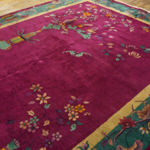High-pile magenta rug with colorful floral motifs and a wide teal border rests on wood planks.
