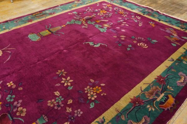 High-pile magenta rug with colorful floral motifs and a wide teal border rests on wood planks.