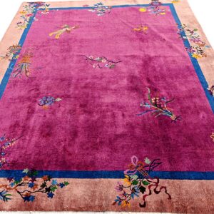 Shiny magenta rug with scattered floral patterns, outlined by a bold blue stripe and a pale peach border.