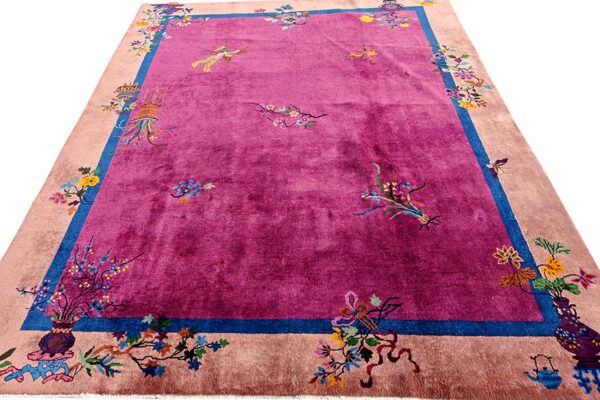 Shiny magenta rug with scattered floral patterns, outlined by a bold blue stripe and a pale peach border.