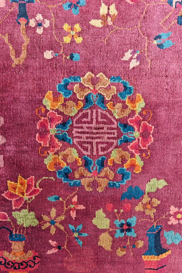Vivid close-up of a magenta rug with multicolored floral elements and a central geometric design.