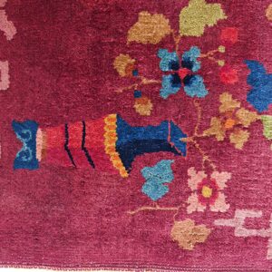 Closeup of a magenta pile rug with a stylized multicolored fish and floral design.