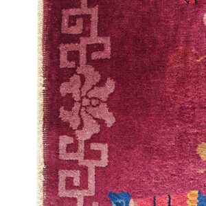 Plush magenta rug detail showing a light pink key-pattern border and colorful abstract designs.