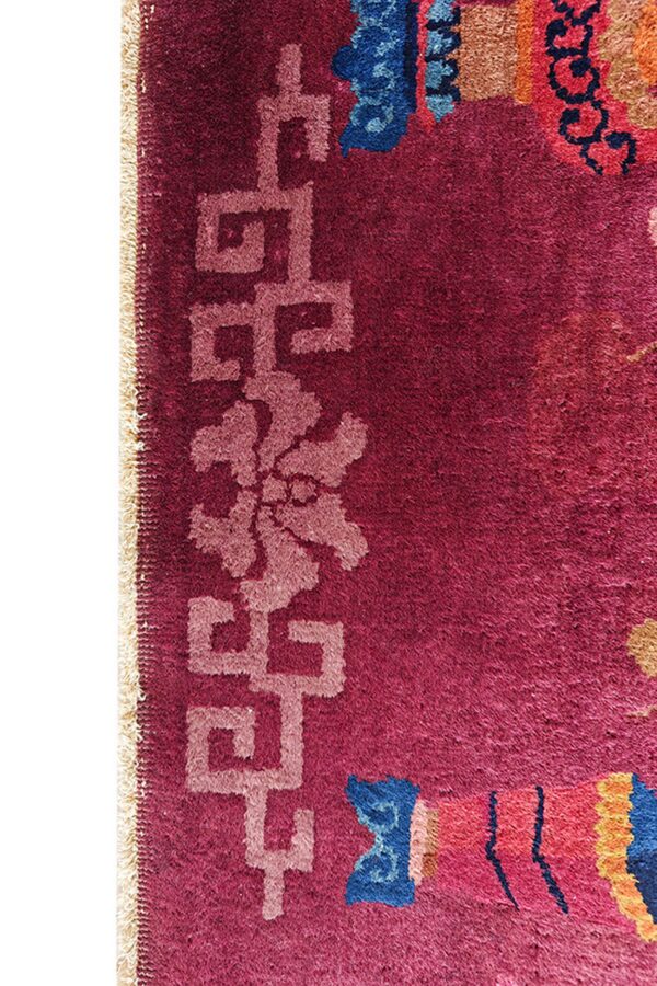 Plush magenta rug detail showing a light pink key-pattern border and colorful abstract designs.