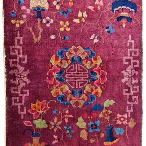 Plum pile rug featuring a multicolored floral and vase design with a light pink fretwork border.