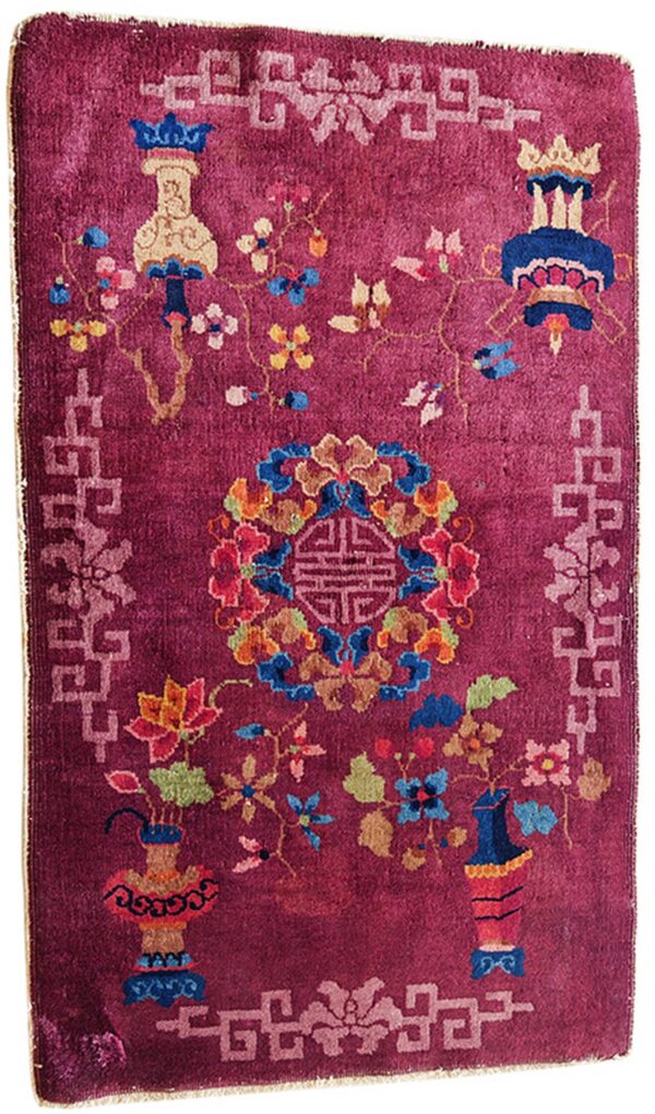 Plum pile rug featuring a multicolored floral and vase design with a light pink fretwork border.