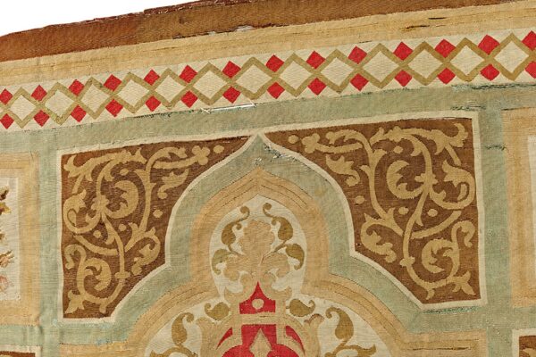 Flatwoven rug detail showing a cartouche pattern in brown, tan, red, and sage green geometric borders.