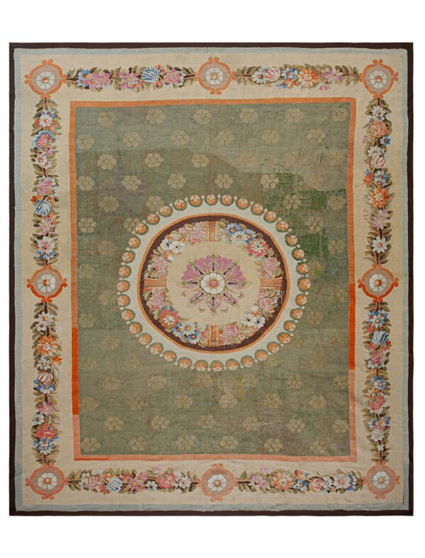 Distressed sage green rug featuring a central floral medallion and a wide cream border with colorful flowering vines.