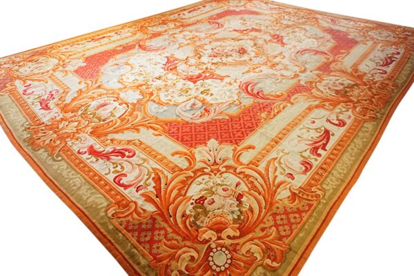 Ornate classical rug in peach, coral, and cream, featuring detailed floral medallions and scrolling borders.