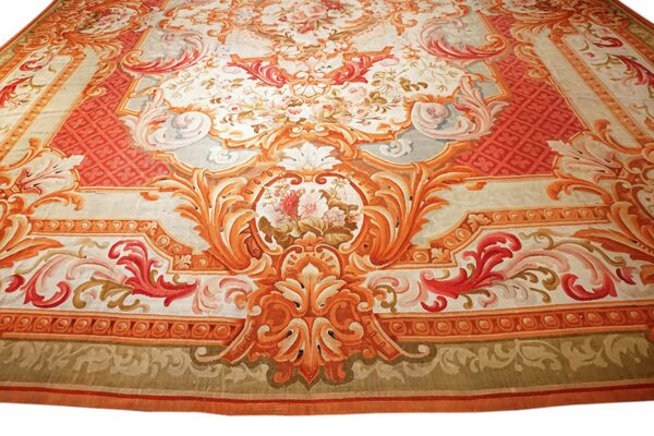 Highly detailed rug displaying complex cartouches and floral bouquets in vibrant orange, red, and cream tones.
