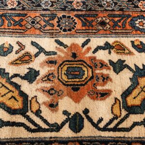 A close-up shows traditional floral and geometric motifs in rust, navy, teal, and cream colors.