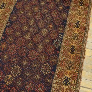 A navy blue runner rug with red and gold geometric patterns rests on distressed light wood floors.