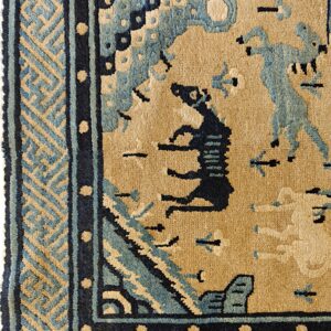 Tan rug detail features dark and light blue figures, surrounded by geometric key and dotted borders.