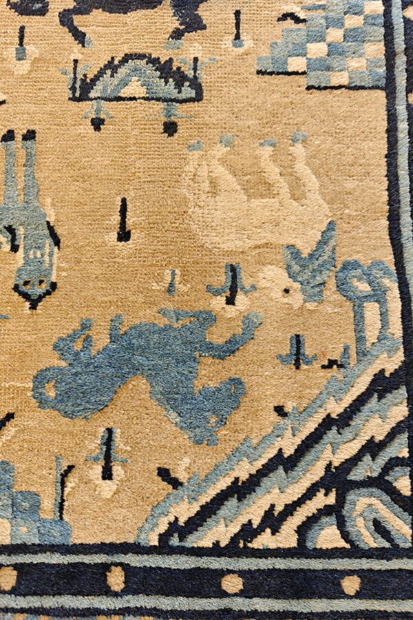 Textured beige rug detail with stylized animal and geometric motifs in light blue and dark navy.