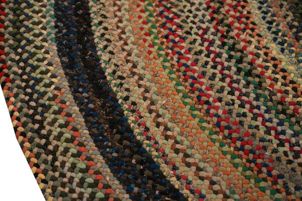 Detail view of a tightly braided rug displaying rich variegated colors like red, orange, green, and dark blue.