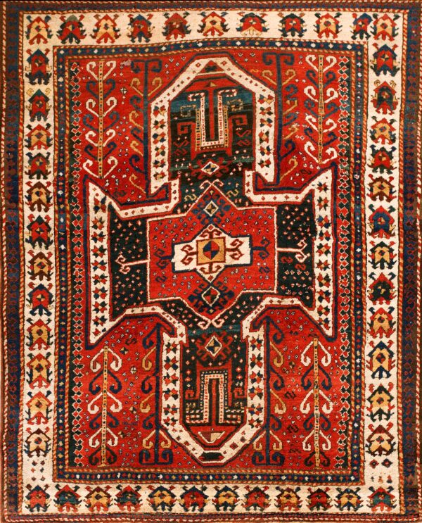 Red and navy tribal rug featuring a central stepped geometric medallion surrounded by patterned cream borders.