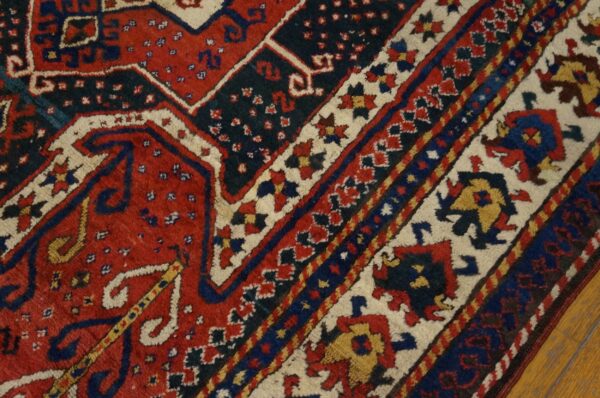 Red, navy, and cream high-pile rug with complex geometric patterns lying on hardwood flooring.