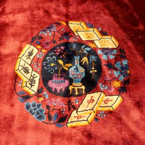 Plush red rug featuring a circular motif of a vase, flowers, and yellow Mahjong tiles.
