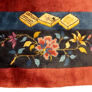 Maroon and black banded rug with a high pile features gold tiles and multicolor floral patterns.