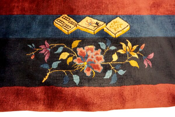 Maroon and black banded rug with a high pile features gold tiles and multicolor floral patterns.
