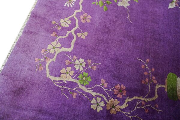 A close-up of a vibrant purple rug featuring a blossoming branch pattern in cream, pink, and green.