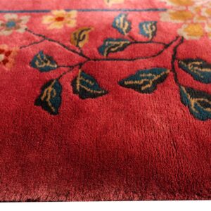 Close-up of a deep red plush rug featuring a floral pattern with gold, cream, and teal leaves.