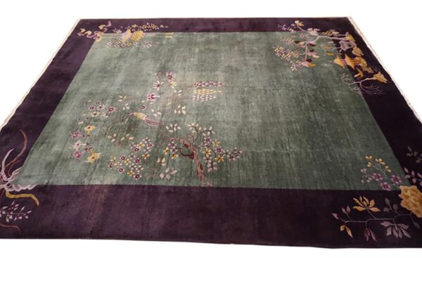 Sage green rug with a dark purple border and scattered pink and yellow flowering branches.