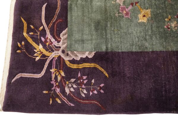 Dark purple border with gold, pink, and taupe floral carving contrasts with a sage green rug field.