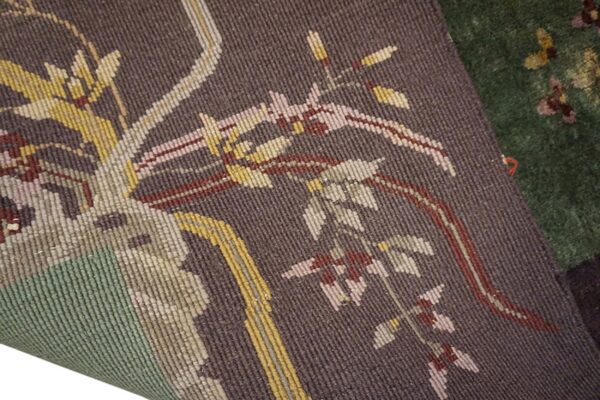 A tightly woven brown rug with stylized botanical patterns in yellow and pink overlays a deep green rug.