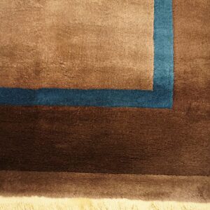 Detail of a plush rug border in shades of brown accented with a teal corner stripe.