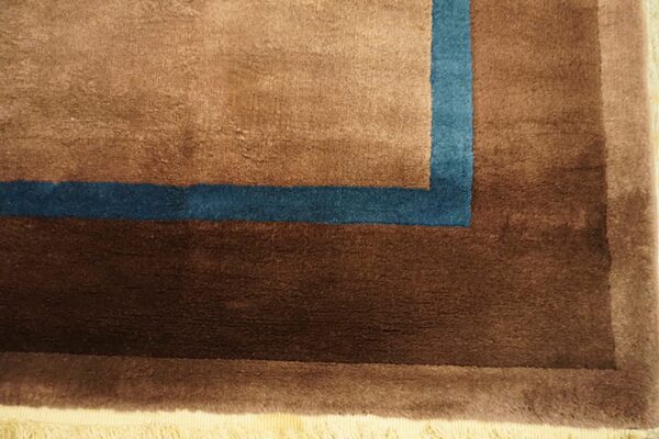 Detail of a plush rug border in shades of brown accented with a teal corner stripe.