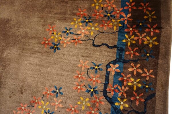 Plush brown rug featuring a stylized design of orange, yellow, and blue flowers on dark branches.