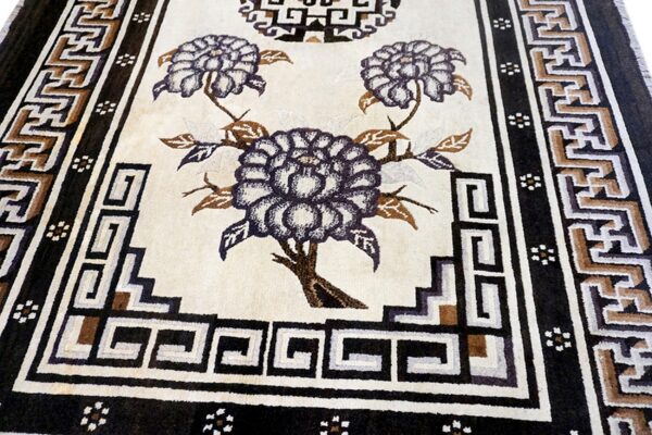 Textured cream rug with dark purple floral patterns and complex geometric borders in black and brown.