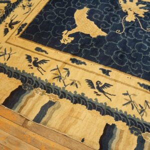 Close-up of a high-pile tan and navy rug showing dragons, birds, and bamboo on wood floorboards.