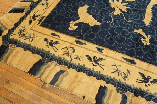 Close-up of a high-pile tan and navy rug showing dragons, birds, and bamboo on wood floorboards.