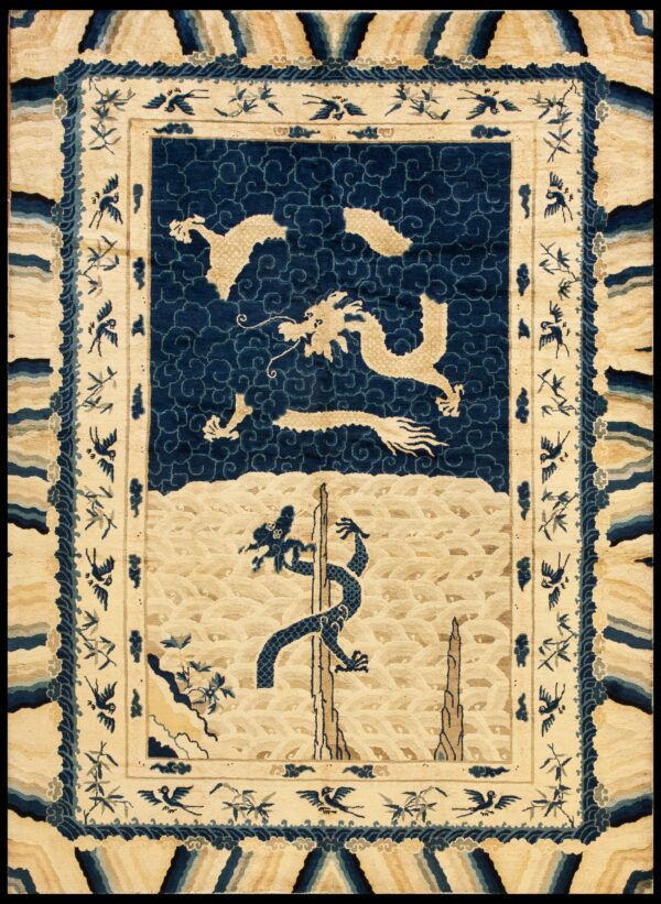 Pictorial rug in cream and navy blue showing dragons, cloud motifs, and a border with birds and bamboo.
