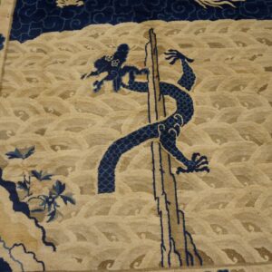 Close view of a tan rug with dark blue dragon, waves, and small border birds.
