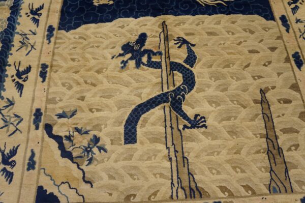 Close view of a tan rug with dark blue dragon, waves, and small border birds.