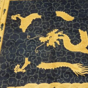 Blue rug with a golden dragon and cloud pattern bordered by stylized birds and light yellow field.