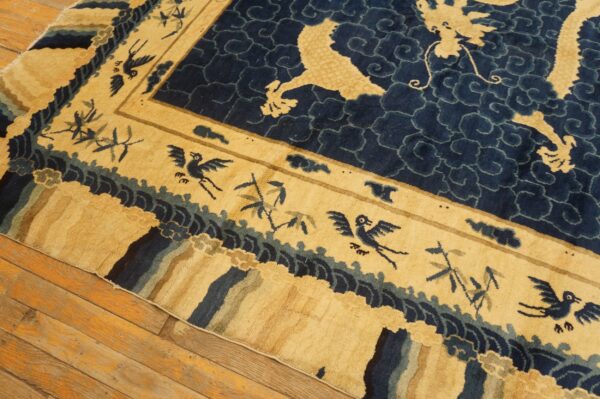 Close-up of a navy and gold rug showing dragon and bird motifs on wood flooring.
