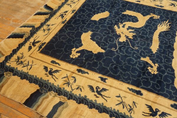 Plush tan and indigo rug featuring a dragon medallion and bird-filled wide border on wood floors.
