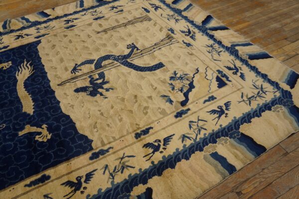 Cream and indigo rug with a mythical dragon and bird pattern resting on distressed wood planks.