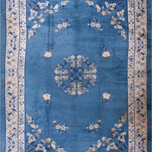 A teal blue rug featuring scattered floral designs and a wide cream border with complex geometric and vine patterns.