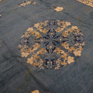 Worn blue rug detail showing a round medallion with navy, cream, and gold floral patterns.