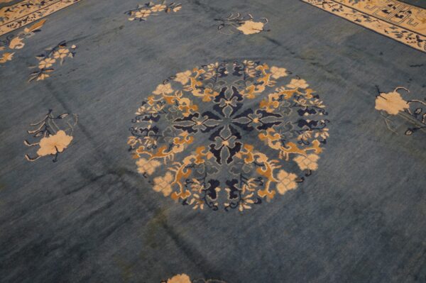 Worn blue rug detail showing a round medallion with navy, cream, and gold floral patterns.